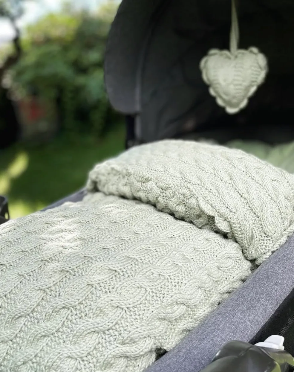 Vognpose i grønn kabelstrikk i vognen ute i hagen